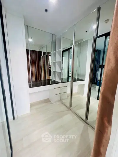Spacious walk-in closet with mirrored doors and ample storage in modern apartment.