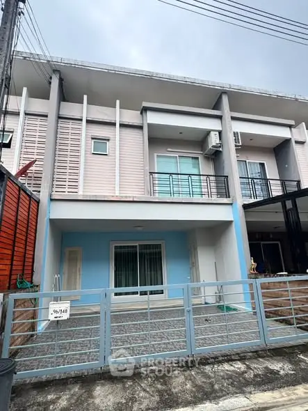 Modern townhouse exterior with balcony and gated entrance, ideal for urban living.