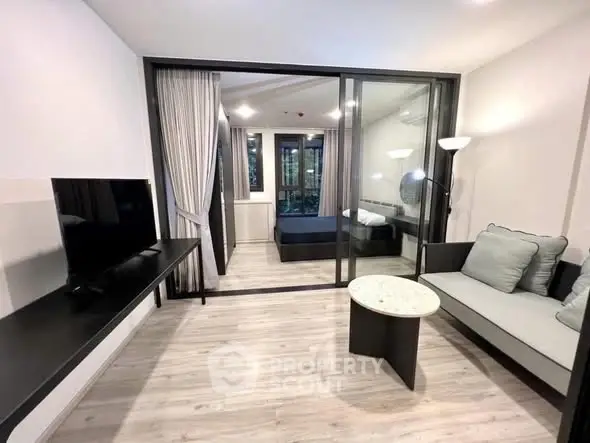 Modern studio apartment with glass partition, sleek furnishings, and cozy ambiance.