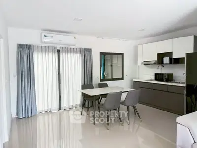Modern open-layout kitchen and dining area with sleek furniture and natural light.