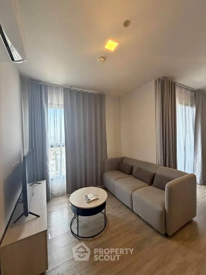 Modern living room with cozy sofa and natural light from large windows.