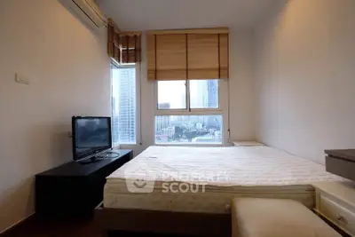 Cozy bedroom with city view, featuring a comfortable bed and modern TV setup.