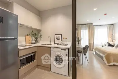 Modern open-layout apartment with kitchen and living area, featuring sleek appliances and cozy decor.