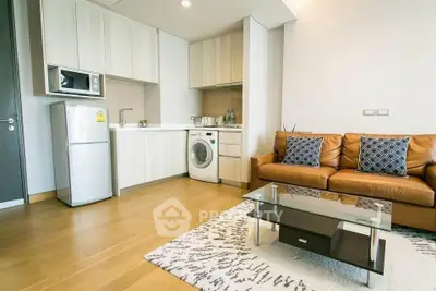 Modern living room with kitchen, featuring a washing machine and stylish decor.