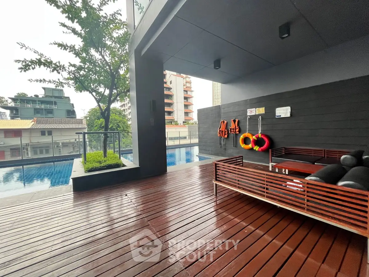 Modern poolside area with wooden deck and seating in urban setting