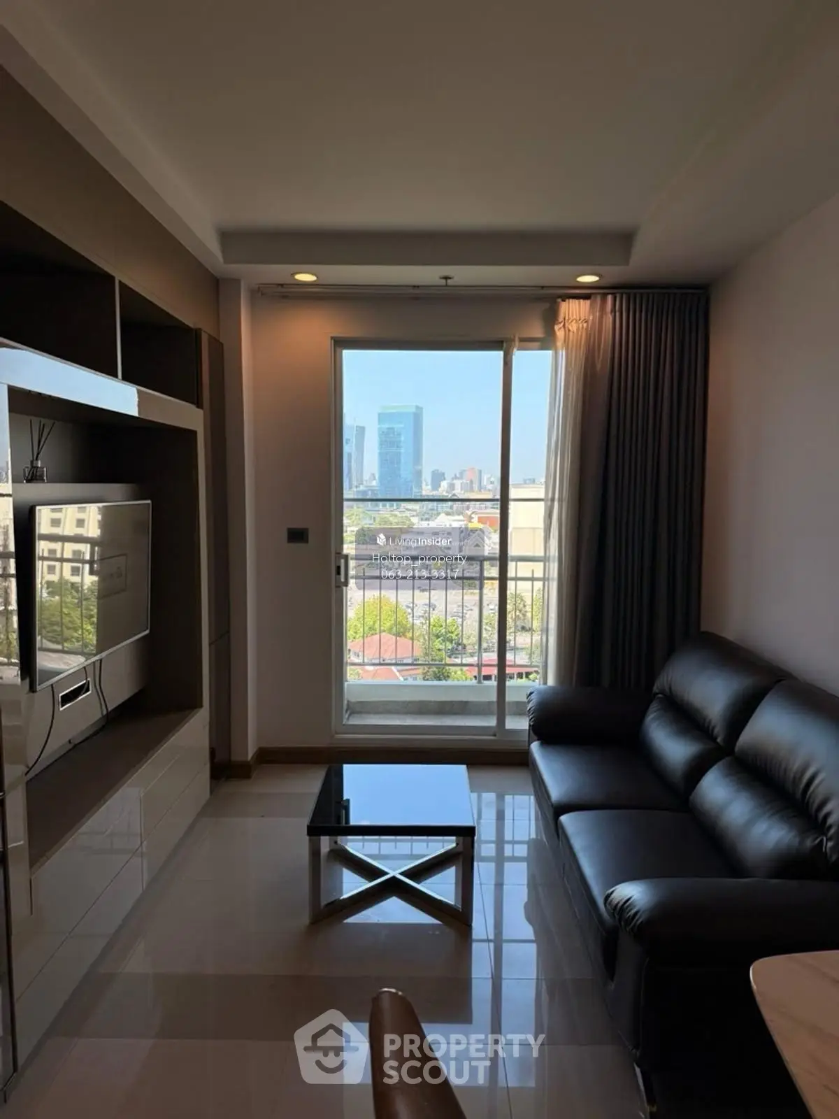 Modern living room with sleek black sofa and city view from large window.