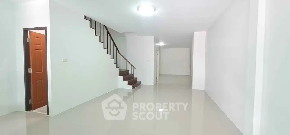 Spacious open-plan living area with sleek staircase and glossy floors