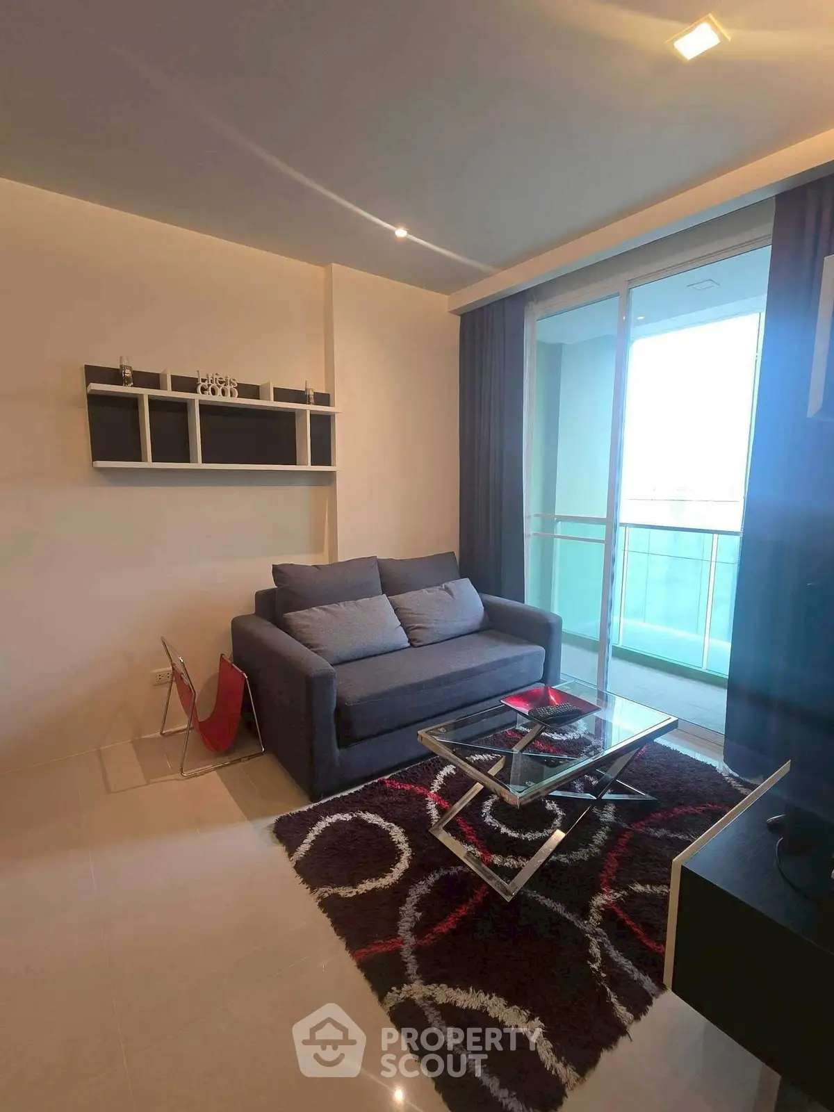 Modern living room with stylish sofa and glass coffee table, featuring a balcony view.