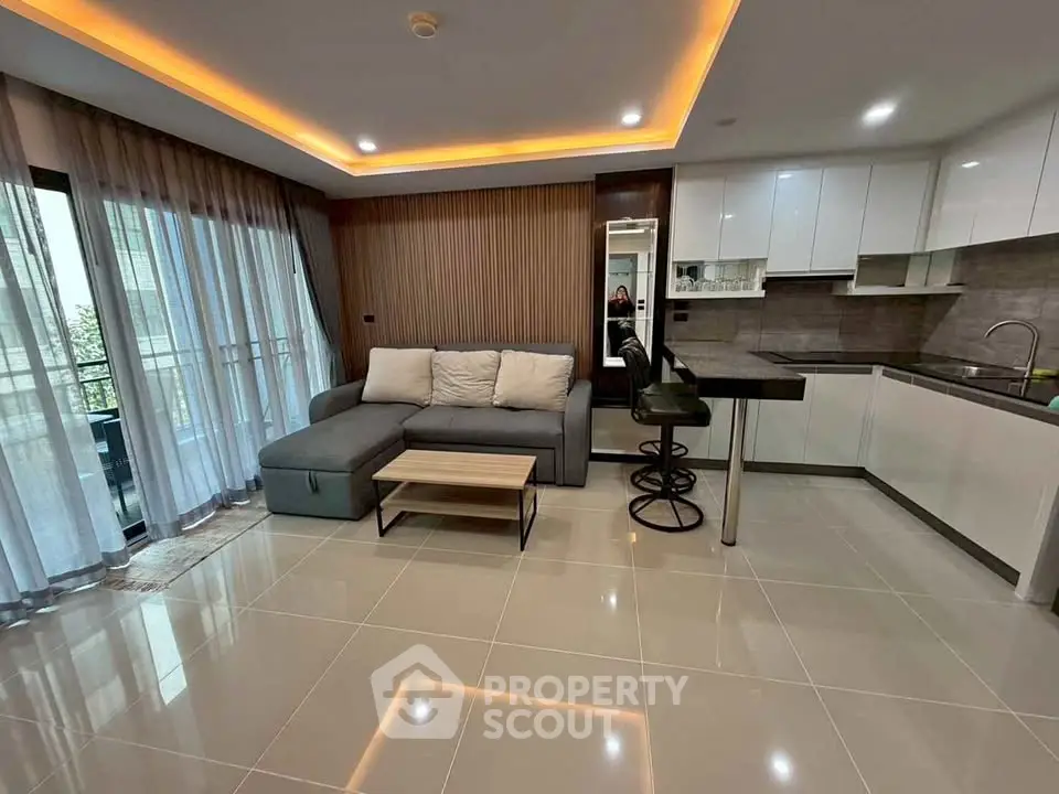 Modern living room with sleek kitchen and stylish lighting in open layout apartment.