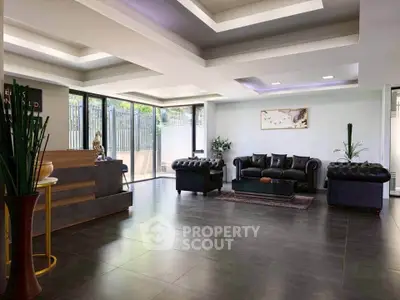 Luxurious modern living room with elegant black leather sofas and large windows offering natural light.