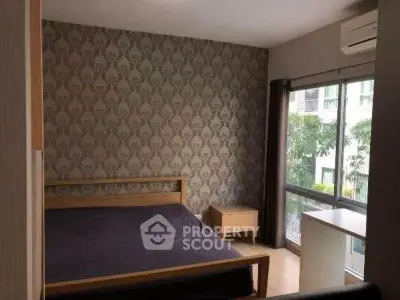 Modern bedroom with stylish wallpaper and large window offering natural light.