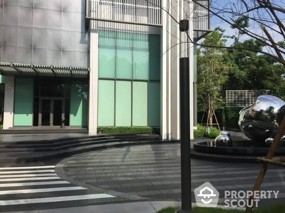 Modern building entrance with sleek design and reflective sculptures