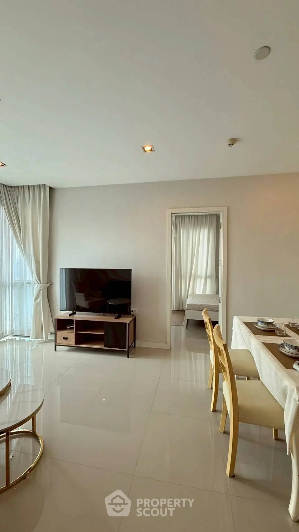 Modern living room with dining area and TV, featuring elegant decor and natural light.
