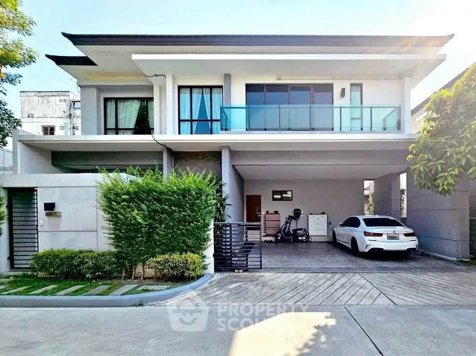 Modern two-story house with spacious driveway and sleek balcony design.