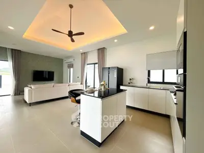 Modern open-layout kitchen and living room with sleek design and ceiling fan.