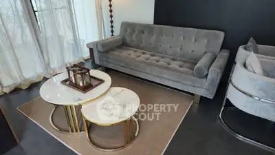 Stylish modern living room with plush gray sofa and elegant marble coffee tables.