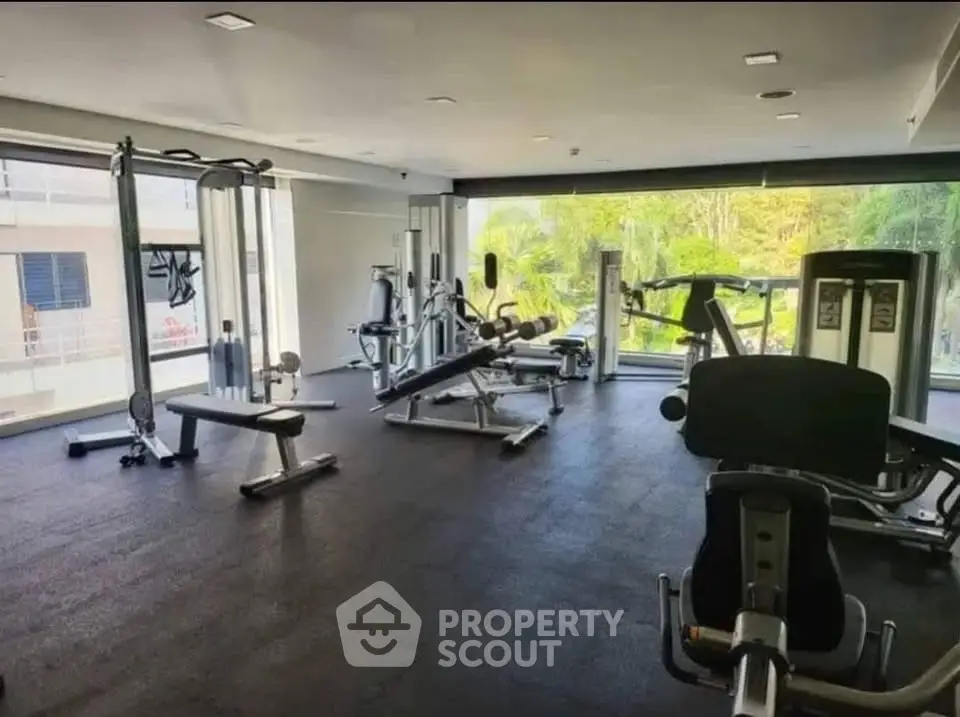 Spacious modern gym with state-of-the-art equipment and large windows offering natural light.