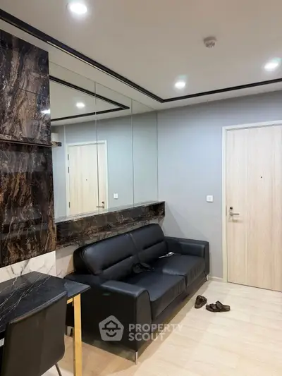 Modern living room with sleek black sofa and marble accents, perfect for stylish urban living.