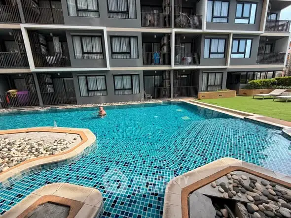 Modern apartment complex with inviting swimming pool and sunbathing area.