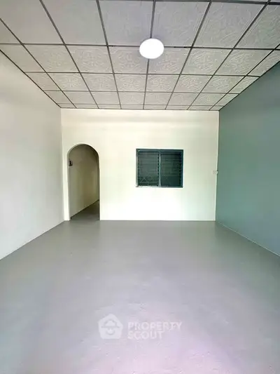 Spacious empty room with unique ceiling design and archway entrance, perfect for customization.