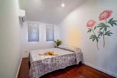 Cozy bedroom with floral wall art and wooden flooring, perfect for relaxation.