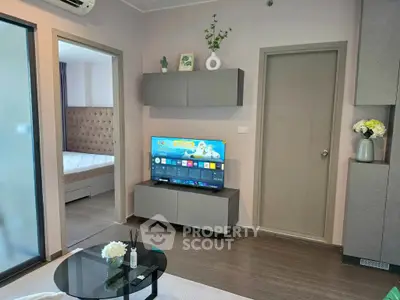 Modern living room with sleek furniture and smart TV, adjacent to a cozy bedroom with elegant decor.