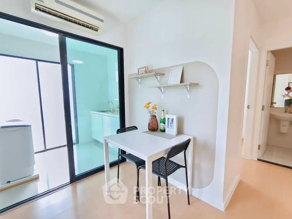 Modern dining area with sleek table and chairs, adjacent to a bright laundry room with washing machine.