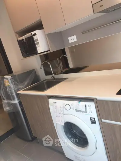 Modern kitchen with washing machine and microwave in sleek design