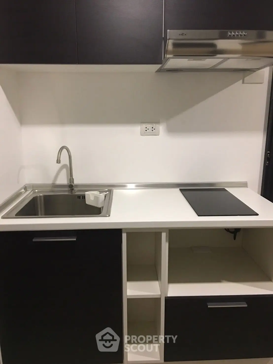 Modern kitchen with sleek black cabinets and stainless steel sink and stovetop.