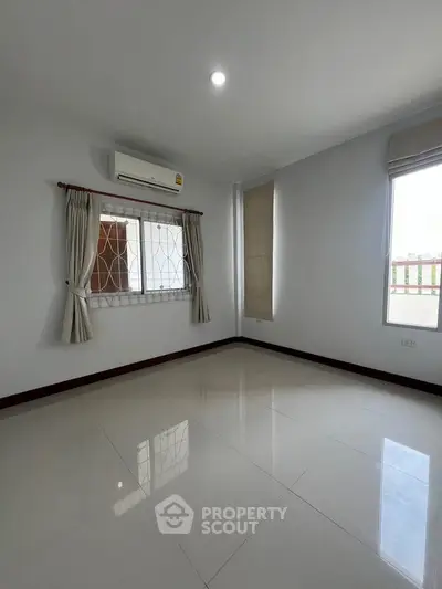Spacious empty room with air conditioning and large windows, perfect for customization.