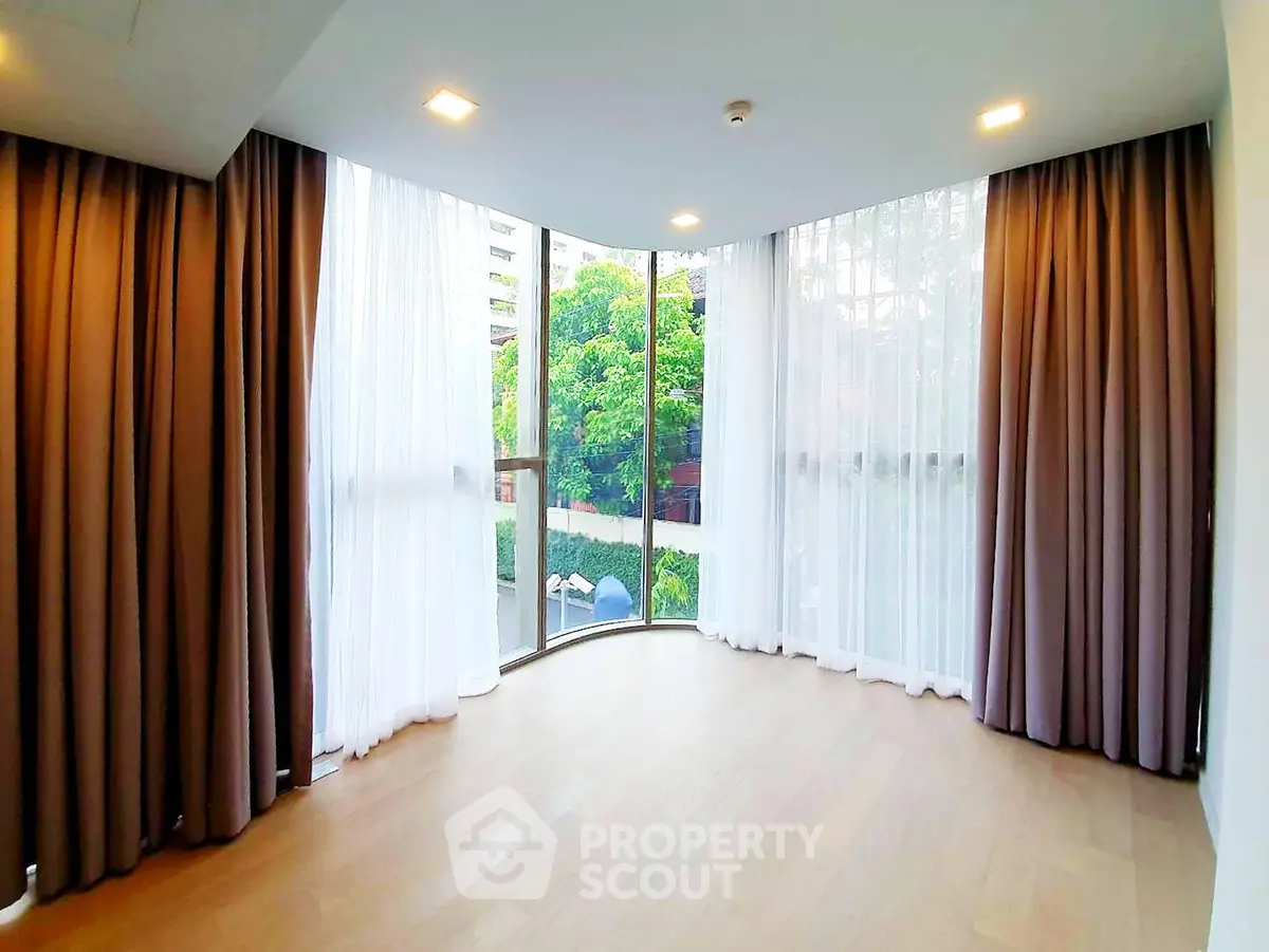 Spacious corner unit with floor-to-ceiling windows and elegant curtains, offering a serene view.