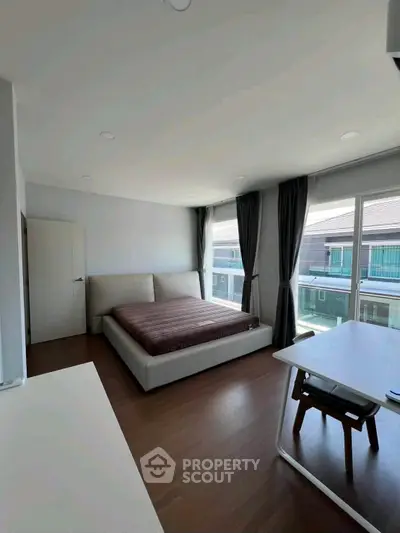 Spacious bedroom with large windows and modern furnishings in a bright, airy setting.