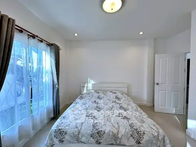 Bright bedroom with large window and cozy bed in modern home.