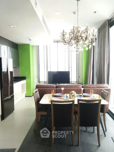 Modern open-layout living room with elegant chandelier and dining area in a stylish apartment.