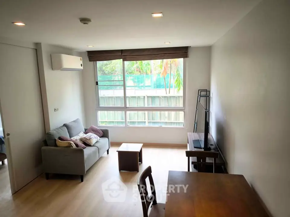 Modern living room with large window and cozy furniture, perfect for relaxation and entertainment.