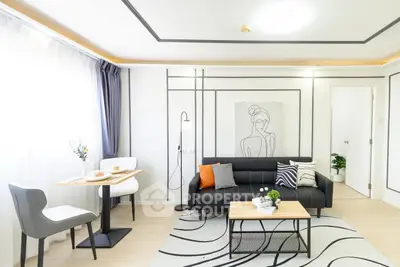 Modern living room with stylish decor, black sofa, and artistic wall design in a bright apartment.
