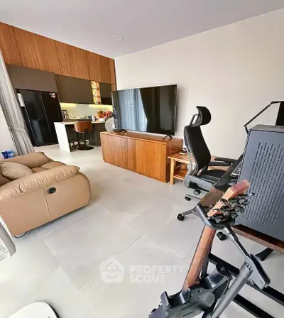 Modern living room with open kitchen, featuring sleek furniture and a large TV, perfect for entertainment.