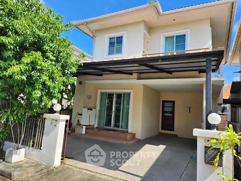 Charming two-story house with covered carport and lush greenery in a serene neighborhood.
