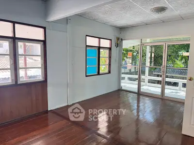 Spacious living room with wooden floors and large windows offering natural light and garden view.