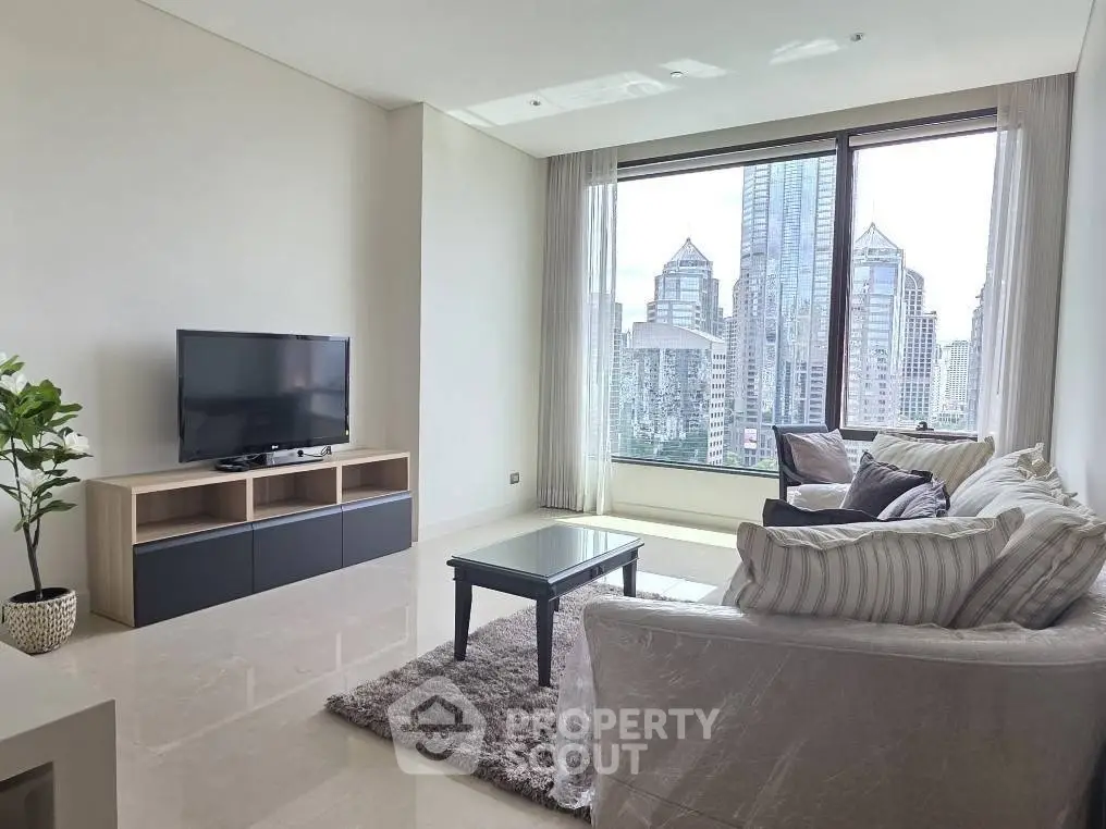 Spacious living room with modern decor and stunning city view from large window.