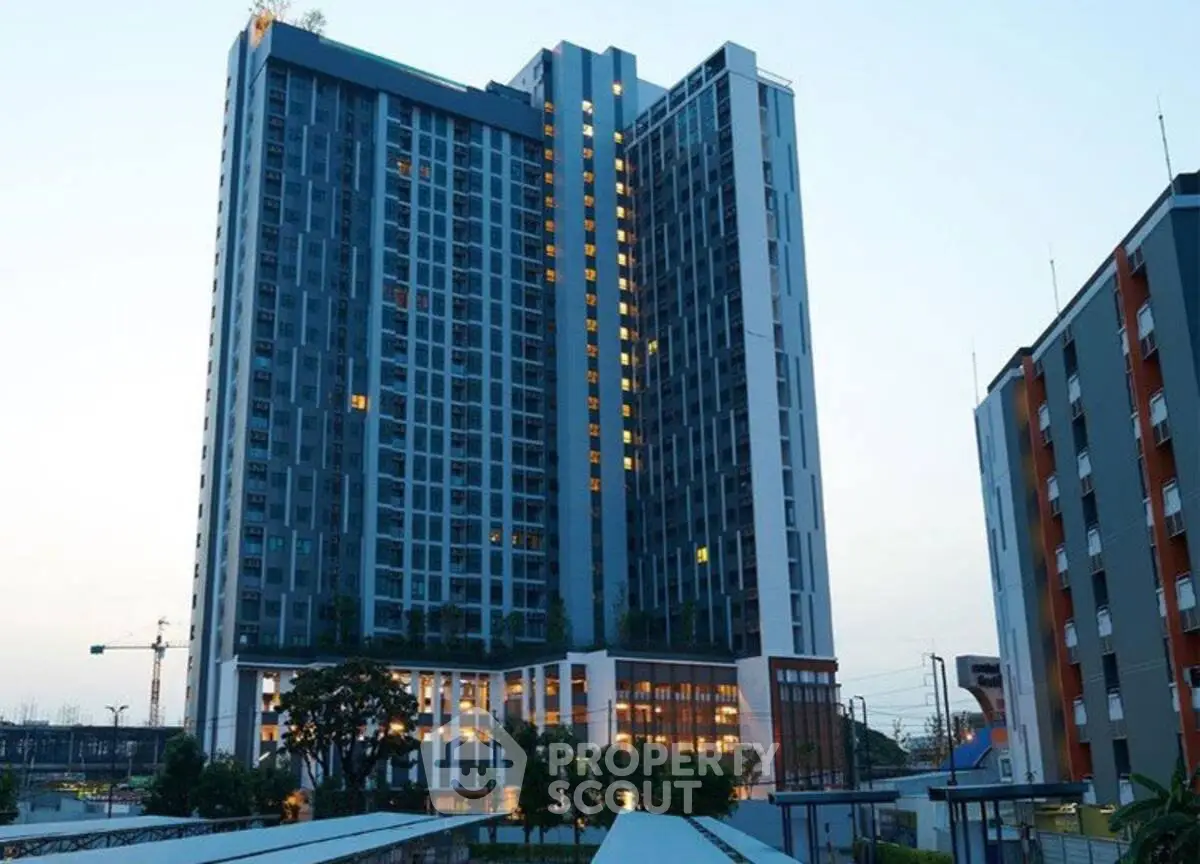 Modern high-rise residential building with illuminated windows at dusk, showcasing urban living.