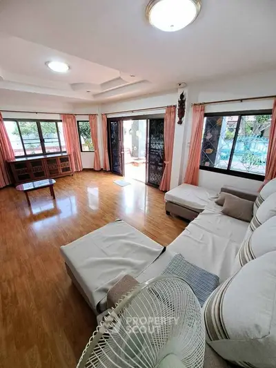 Spacious living room with large windows and wooden flooring, perfect for natural light and comfort.