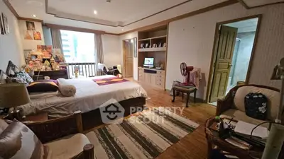 Spacious bedroom with cozy decor and city view, featuring wooden flooring and ample natural light.