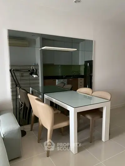 Modern dining area with sleek glass table and beige chairs in stylish apartment.