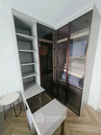 Modern study room with sleek glass cabinets and stylish desk in a contemporary apartment.
