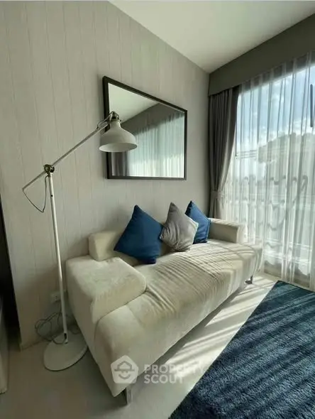 Modern living room with cozy sofa, floor lamp, and large window with natural light.