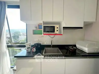 Modern kitchen with sleek white cabinets and large window offering natural light and scenic view.