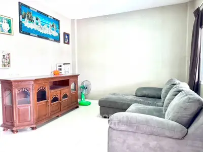 Spacious living room with plush gray sofa and elegant wooden cabinet, perfect for relaxation and entertainment.