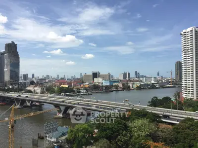 Stunning cityscape view with river and modern high-rise buildings under a clear blue sky.