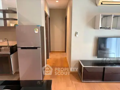 Modern apartment interior with sleek kitchen and cozy living area featuring wooden flooring and stylish decor.